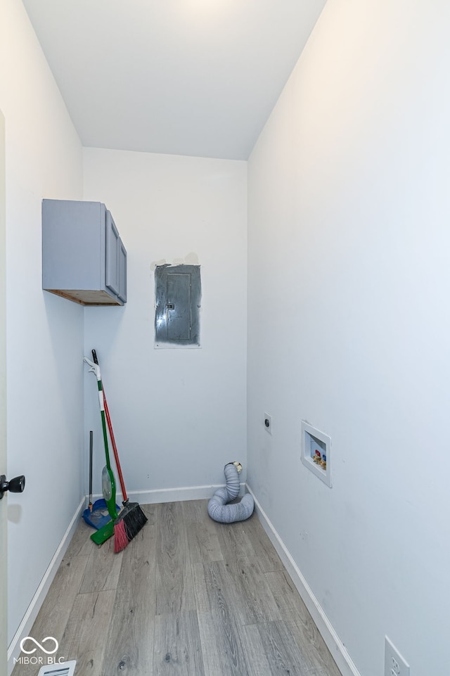 clothes washing area with hookup for a washing machine, baseboards, electric panel, cabinet space, and light wood-style floors