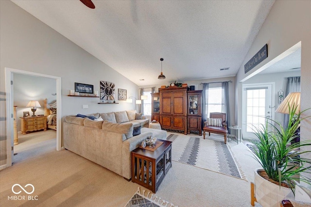 living room featuring visible vents, light colored carpet, high vaulted ceiling, and a textured ceiling