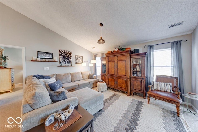 living room with light carpet, visible vents, a textured ceiling, and high vaulted ceiling