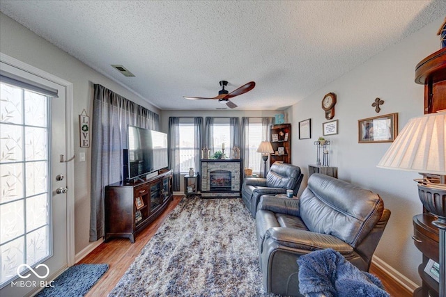 living room featuring visible vents, ceiling fan, a textured ceiling, and light wood-style floors