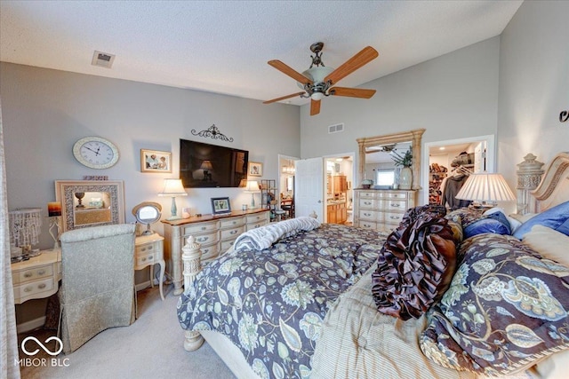 carpeted bedroom with a walk in closet, a textured ceiling, visible vents, and a closet