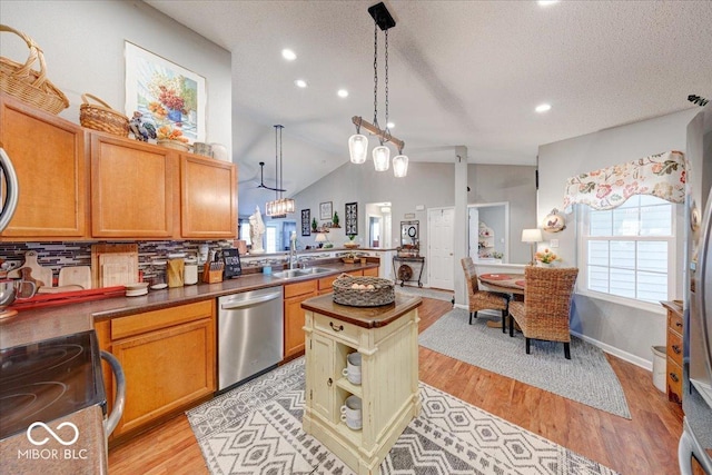 kitchen with a sink, vaulted ceiling, light wood-style floors, a textured ceiling, and stainless steel dishwasher