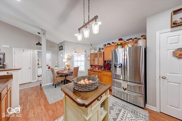 kitchen with pendant lighting, lofted ceiling, light wood-style floors, stainless steel refrigerator with ice dispenser, and a textured ceiling