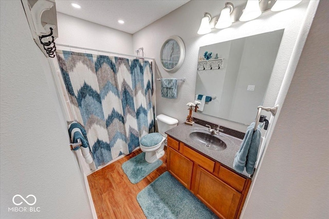 bathroom with toilet, vanity, a shower with shower curtain, and wood finished floors