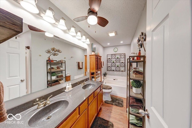 bathroom with a textured ceiling, wood finished floors, a ceiling fan, and a sink