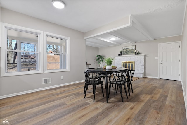 dining space featuring visible vents, baseboards, beamed ceiling, and wood finished floors