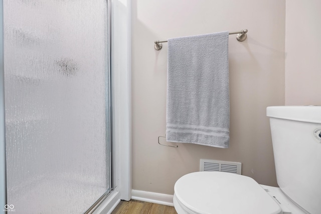 full bath featuring visible vents, toilet, a stall shower, wood finished floors, and baseboards