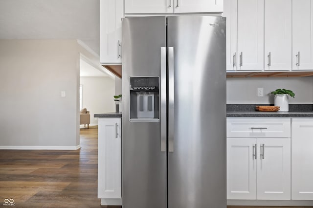 kitchen with dark wood-style floors, stainless steel fridge, baseboards, and white cabinets