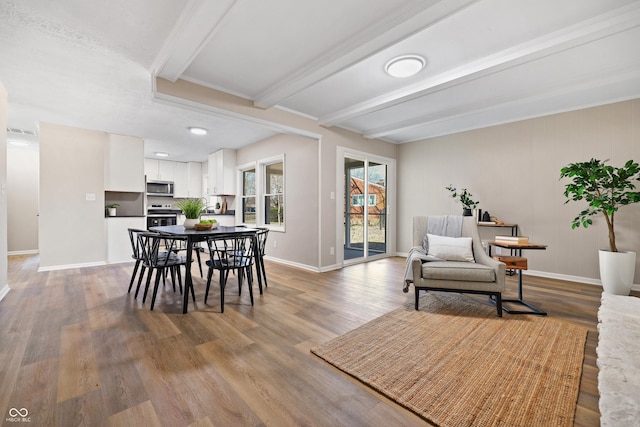 dining space with beamed ceiling, visible vents, baseboards, and wood finished floors