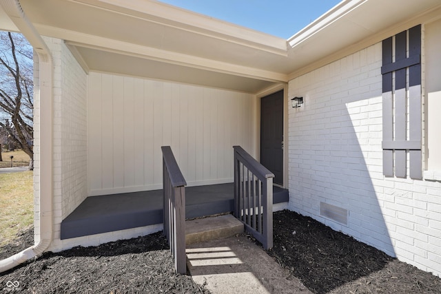 entrance to property featuring crawl space and brick siding