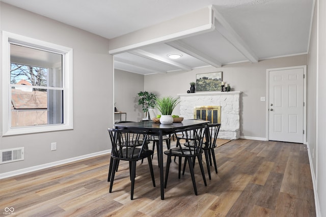 dining room featuring visible vents, beamed ceiling, baseboards, and wood finished floors