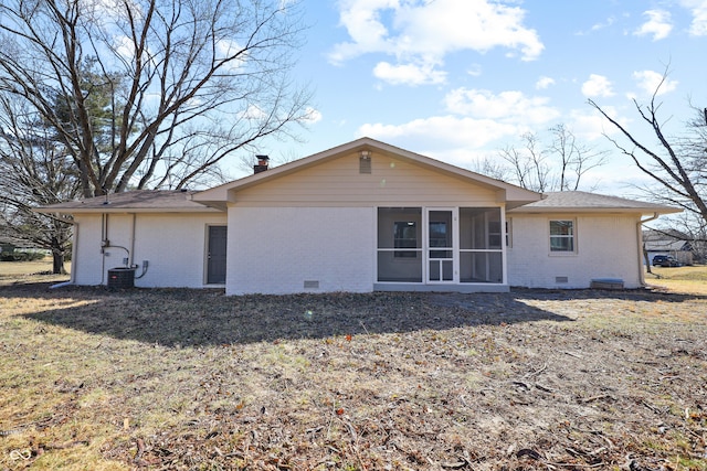 rear view of property featuring a yard, a sunroom, crawl space, brick siding, and a chimney