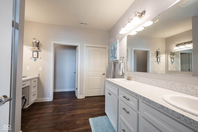 full bath featuring a sink, visible vents, wood finished floors, and double vanity