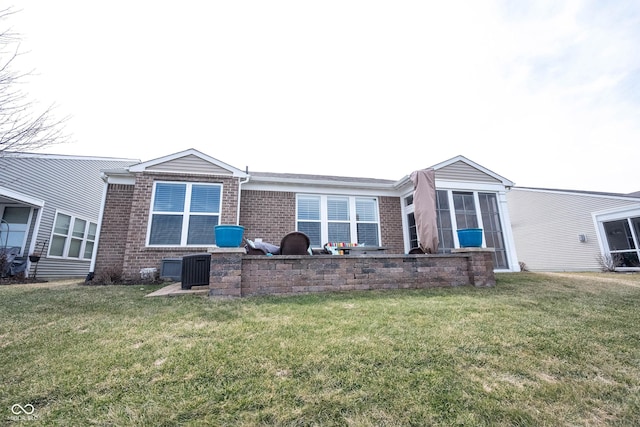 back of property featuring brick siding and a yard