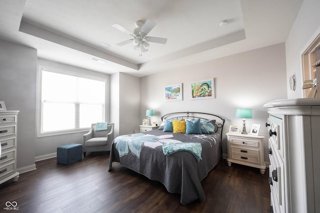 bedroom featuring dark wood finished floors, visible vents, and a tray ceiling