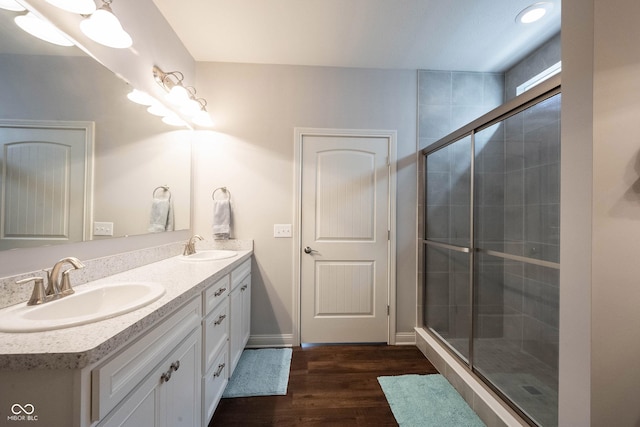 bathroom with a sink, wood finished floors, a stall shower, and double vanity