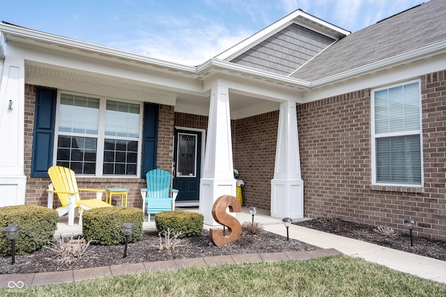 view of exterior entry featuring brick siding and covered porch