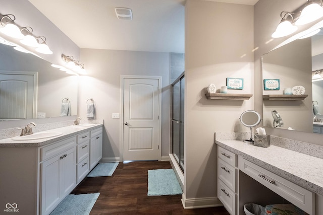 bathroom with double vanity, wood finished floors, a stall shower, and a sink