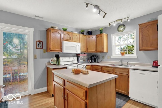 kitchen featuring visible vents, light wood-style flooring, a sink, white appliances, and light countertops