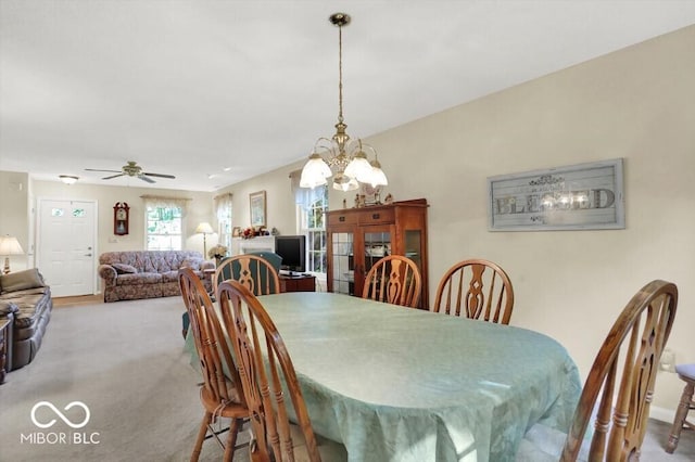 carpeted dining room with ceiling fan with notable chandelier