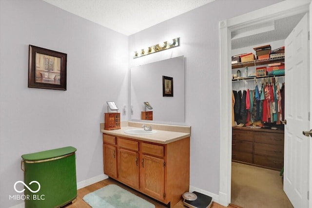 bathroom with vanity, baseboards, and a textured ceiling