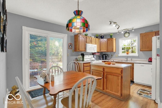 kitchen featuring a sink, a textured ceiling, white appliances, light wood-style floors, and light countertops