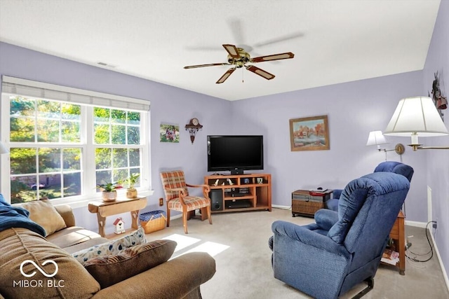 living room featuring baseboards, light colored carpet, and a ceiling fan