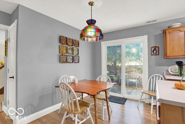 dining area featuring visible vents, light wood-type flooring, and baseboards