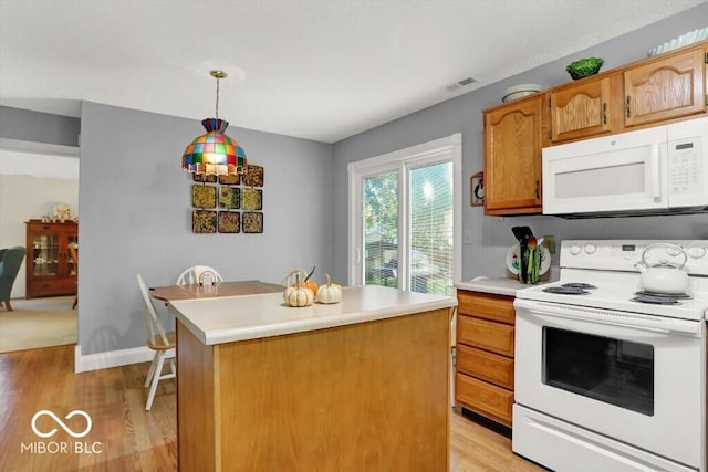 kitchen featuring visible vents, white appliances, a kitchen island, and light countertops