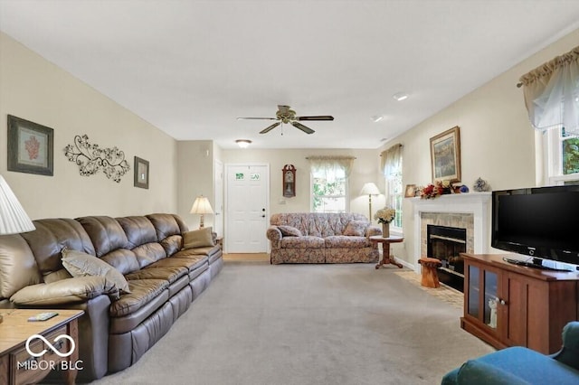 carpeted living room featuring a tile fireplace and a ceiling fan