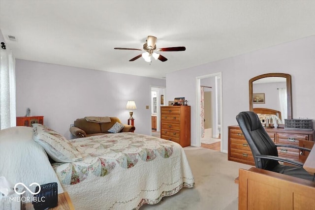 bedroom featuring light carpet, visible vents, ensuite bath, and ceiling fan