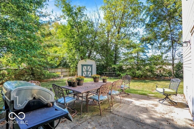 view of patio with grilling area, fence, outdoor dining area, an outdoor structure, and a storage unit