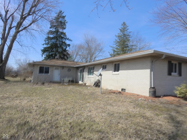 back of property with crawl space and brick siding