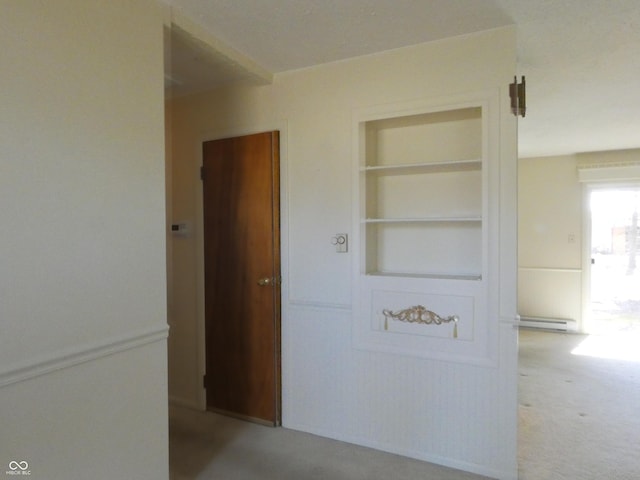 hallway featuring a baseboard heating unit, built in shelves, and carpet flooring