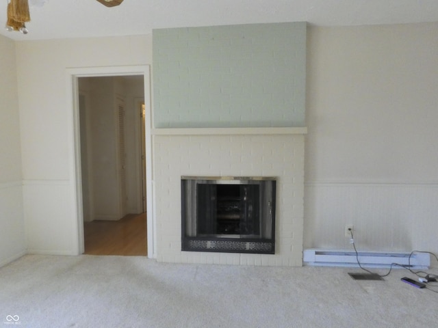 unfurnished living room featuring a wainscoted wall, a brick fireplace, a ceiling fan, and carpet