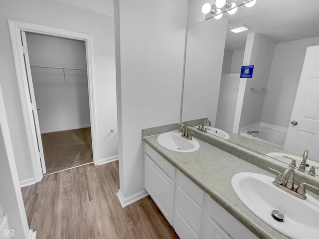 full bath featuring a bath, wood finished floors, and a sink