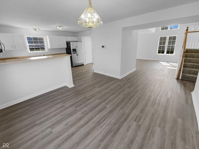 unfurnished living room featuring stairway, baseboards, and dark wood finished floors