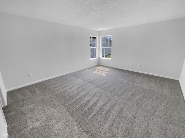 carpeted empty room with a textured ceiling and baseboards