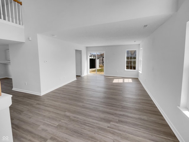 unfurnished living room featuring visible vents, baseboards, and wood finished floors