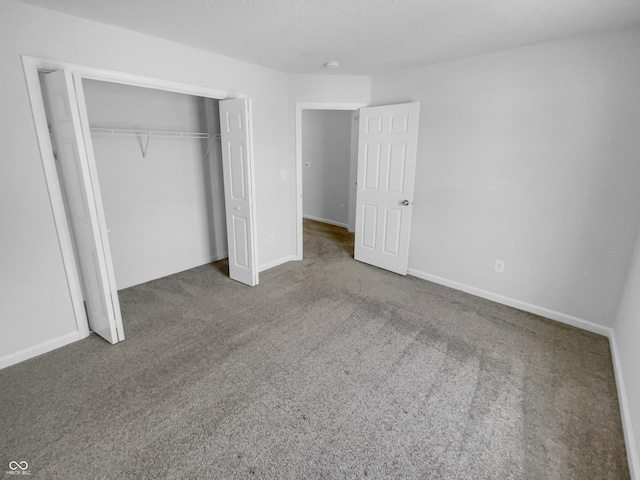 unfurnished bedroom with carpet, a closet, and baseboards