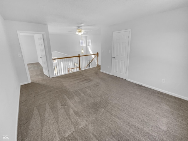 carpeted spare room featuring a ceiling fan and baseboards