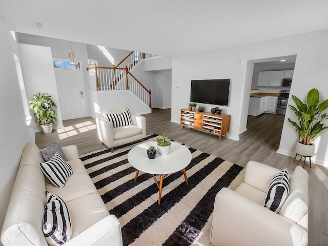 living room featuring visible vents, stairs, baseboards, and wood finished floors