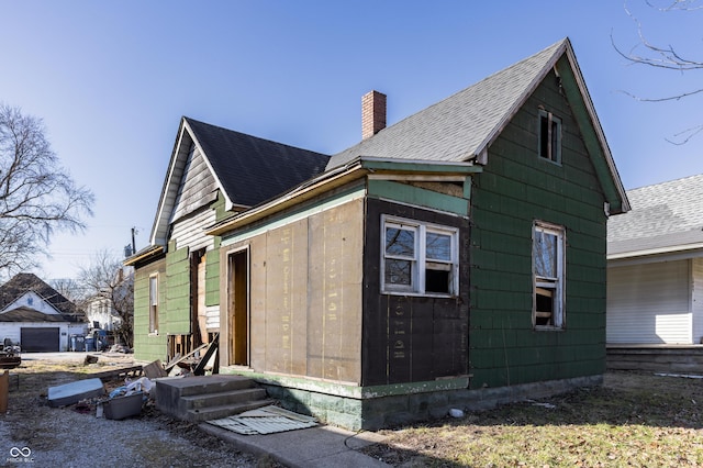 view of property exterior featuring roof with shingles and a chimney