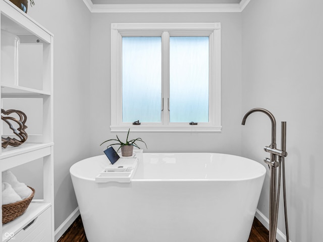 full bathroom featuring a soaking tub, baseboards, and ornamental molding