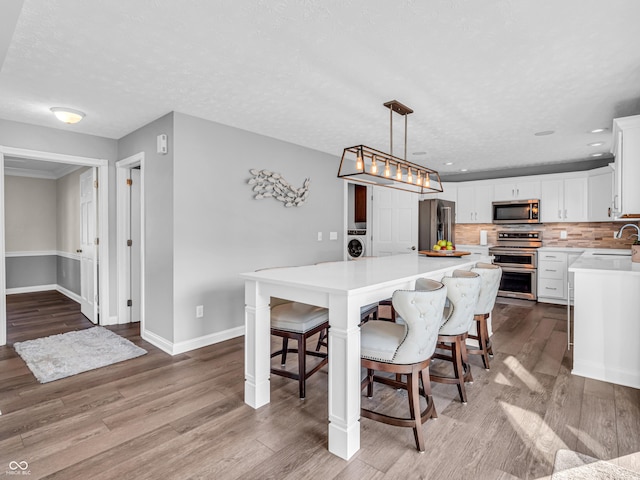 dining room featuring baseboards, recessed lighting, wood finished floors, washer / clothes dryer, and a textured ceiling