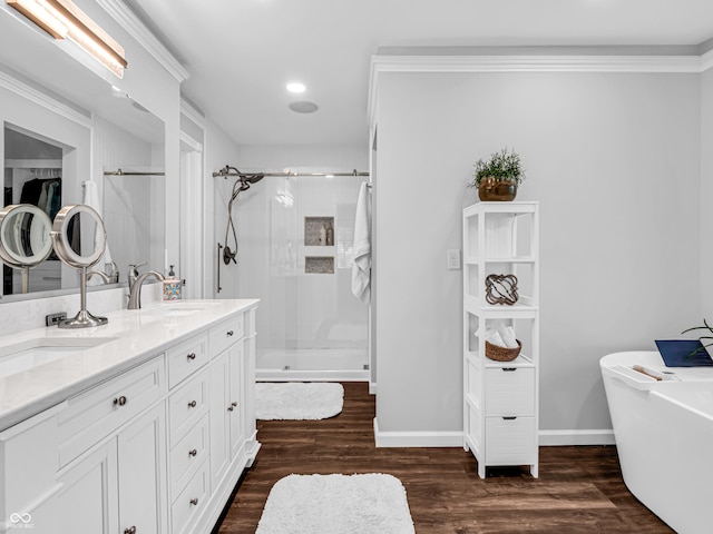 bathroom featuring a stall shower, a sink, wood finished floors, baseboards, and a freestanding bath