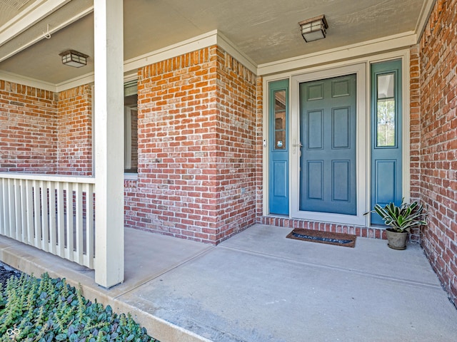 doorway to property featuring a porch and brick siding