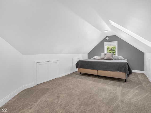 bedroom with lofted ceiling with skylight, carpet flooring, and baseboards