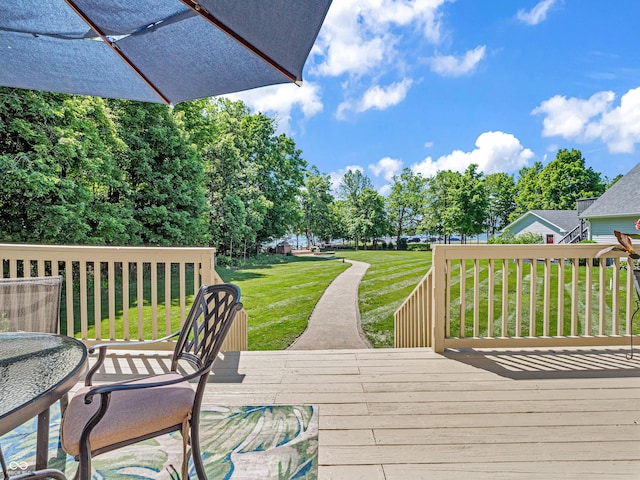 wooden deck with outdoor dining space and a yard