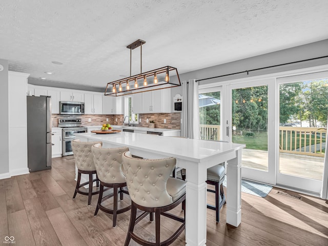 kitchen featuring stainless steel appliances, wood-type flooring, a healthy amount of sunlight, and light countertops